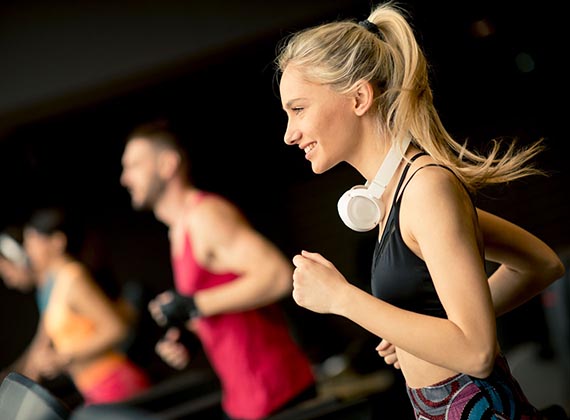 young people running on treadmills in modern gym